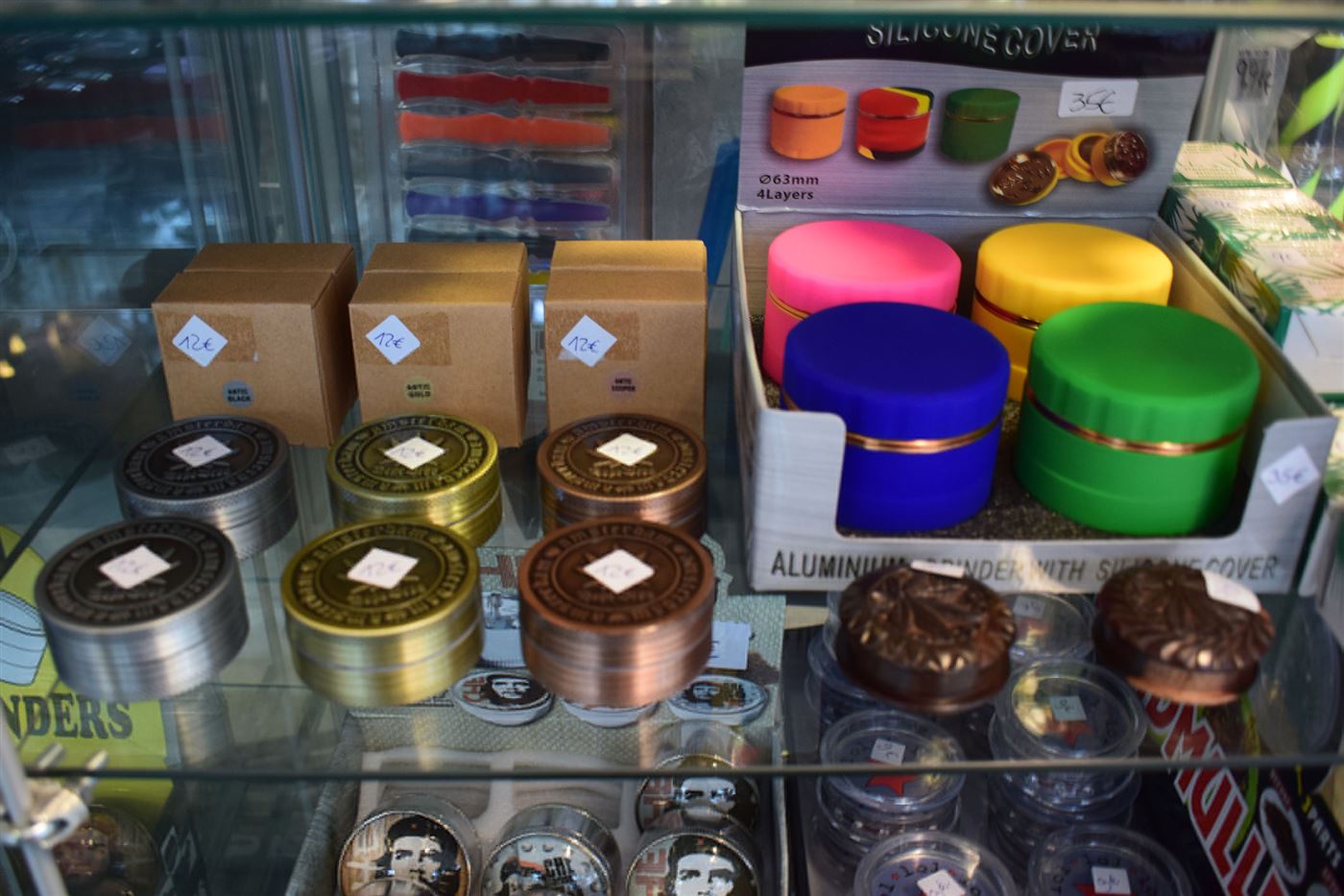 Vitrine mit bunten Grindern und Dosen im Headshop